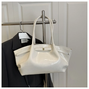 Detalle del bolso tote en cuero charol blanco roto con hebilla dorada y asas delgadas