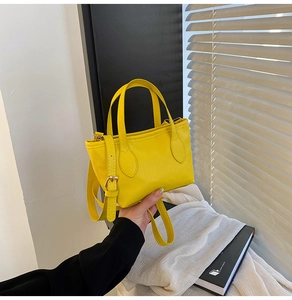 Close-up of yellow bucket bag with lychee grain texture and adjustable strap in use