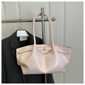 Detalle de bolso de charol rosa claro con textura brillante y hebilla de metal dorado