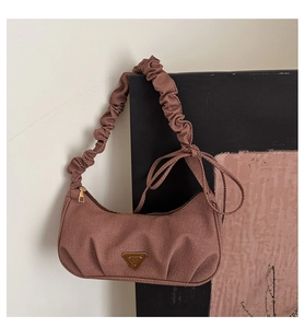 Detail of scrunched shoulder strap and triangle metal logo on brown corduroy hobo bag