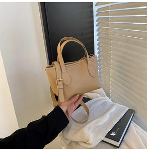 Detail of light brown bucket bag in lychee leather with adjustable strap and gold hardware