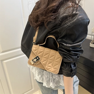 Petit sac bandoulière marron matelassé avec fermoir chaîne sur fond minimaliste