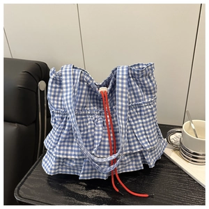 Detail view of blue gingham tote bag featuring layered ruffles and red drawstring closure