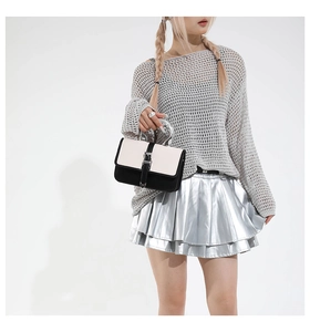 Detail of a chic black and white contrast handbag with unique silver metallic curved handle