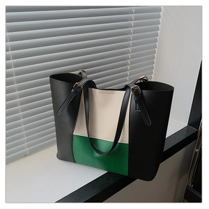 Detail of color-block tote bag featuring black and beige panels with metal hardware