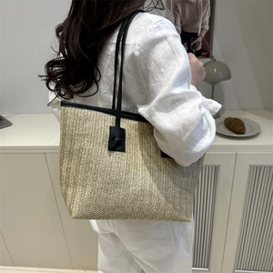 Grande borsa tote in paglia intrecciata beige con finiture nere indossata da modella