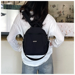 Rear view of a model wearing a black nylon mini backpack in a cafe setting