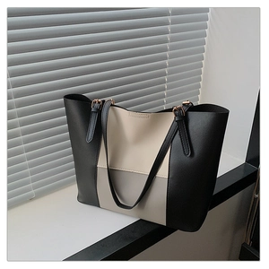 Detail view of large patchwork tote bag featuring metal buckles and textured faux leather