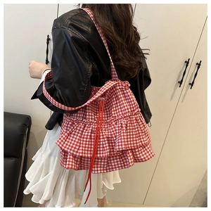 Detail of red gingham tote bag with layered ruffles and drawstring on a model