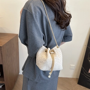 Woven drawstring bucket bag with gold chain strap and pearl charms for summer