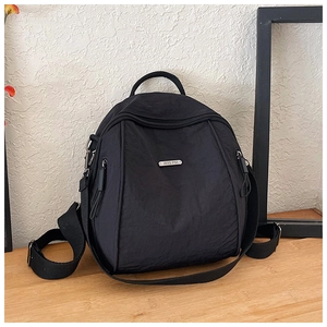 Close-up of lightweight black nylon backpack with metal brand logo and zippers