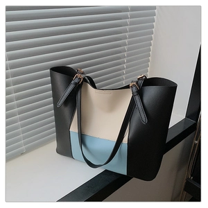 Close-up of color-block tote bag featuring golden hardware and adjustable strap detail