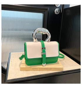 Detail of green and beige leather handbag with unique curved silver metal handle