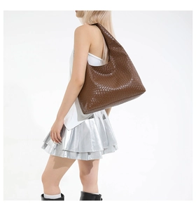 Detailed shot of large brown woven leather hobo bag worn by model for casual style
