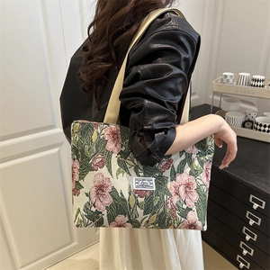 Borsa tote jacquard retrò a fiori con manici in cotone crema mostrata a tracolla su modella