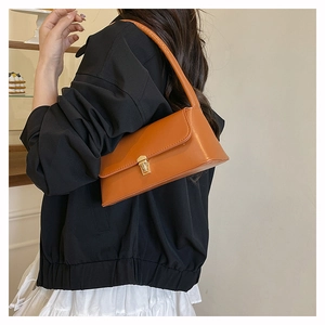 Caramel leather baguette bag with gold square lock shown on shoulder in a side view