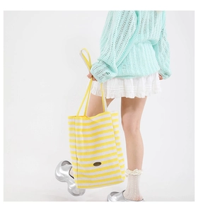 Close-up of yellow and white striped canvas tote bag with brown leather patch detail
