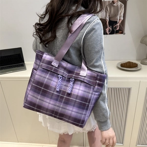 Borsa tote a quadri viola con ampi spallacci indossata da una modella in ufficio