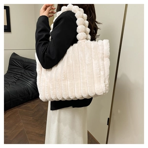 Close-up of white plush tote bag featuring vertical stripes and unique pom-pom handles
