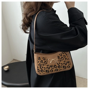 Détail du sac baguette imprimé léopard avec nœud en métal et bandoulière élégante sur le côté