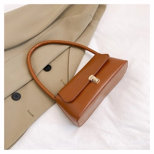 Gros plan d'un sac baguette en similicuir marron avec une boucle en métal doré chic
