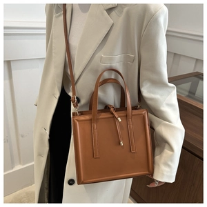 Detailed view of brown leather briefcase featuring fine stitching and tassel detail