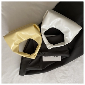 Detail of minimalist dumpling handbags with glossy oil wax texture and knotted handle