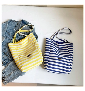 Flat lay of colorful striped canvas tote bags with vintage logo and denim jacket accent