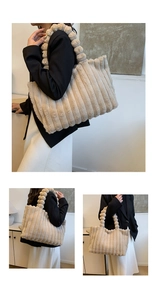 Detail of beige plush tote bag featuring vertical ribbed texture and pom-pom handle