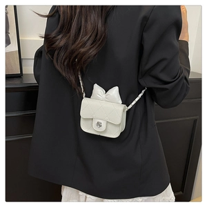 Close-up of white quilted leather mini bag with bow detail and camellia metal clasp