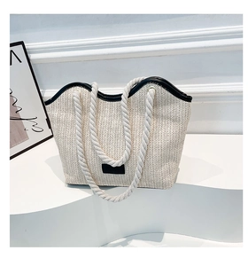 Gros plan du sac cabas en paille tressée avec poignées en corde et patch en cuir noir