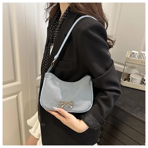 Detail of light blue woven hobo bag featuring golden bow buckle and slim shoulder strap