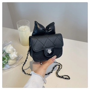 Detail of silver camellia buckle on black quilted bag with chain strap and bow decor