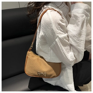 Detail of camel woven texture and gold bow ornament on a chic French shoulder bag