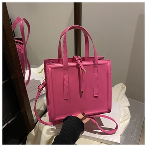 Detail of pink structured tote bag with gold metal drawstring tips and decorative straps
