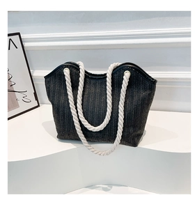 Détail du sac cabas tissé noir avec anses en corde de coton blanc sur support épuré