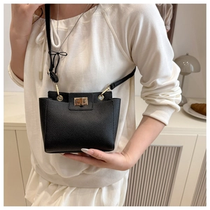 Gros plan du sac à main noir en cuir grainé avec fermoir tournant doré et bandoulière