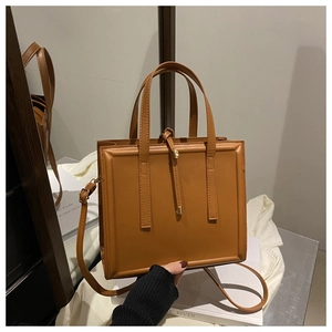 Detail of a brown square tote bag in PU leather featuring an embossed frame and knotted cord