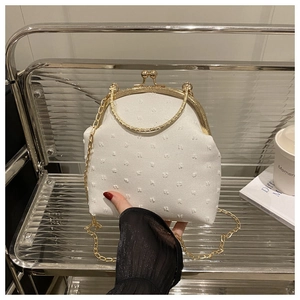 Detalle del bolso vintage blanco con textura de puntos y correa de cadena dorada
