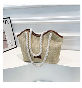 Détail du sac cabas en paille tressée avec poignées en corde épaisse et finitions en cuir brun