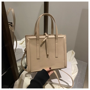 Detailed view of beige leather shoulder bag with slim handles and adjustable strap