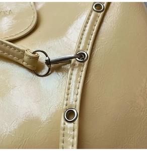 Close-up of cream textured leather bag with silver metal hooks and precise stitching