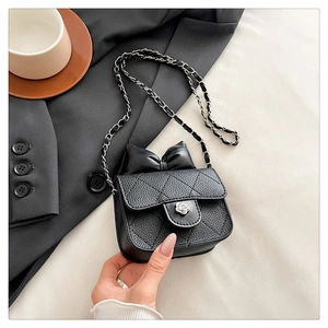 Detail of black quilted leather mini bag featuring bow and floral silver clasp