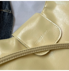 Close-up of cream textured leather bag with embossed logo and fine stitching detail