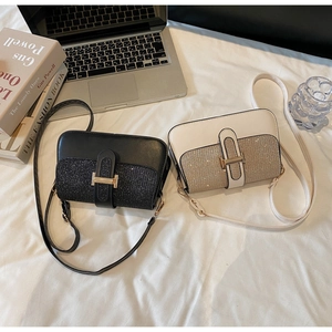 Close-up of stylish rectangular flap bags in black and cream with glitter textured finish