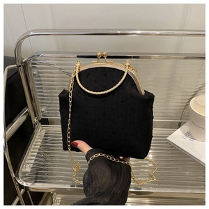 Detalle de la tela de lunares negros y el cierre vintage dorado en este elegante bolso de noche