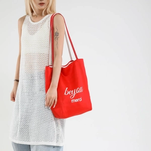 Red contrast canvas tote bag with beyou merci print paired with white crochet top