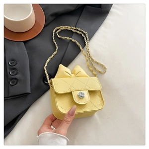 Detailed macro view of yellow quilted mini bag with decorative bow and floral metal buckle