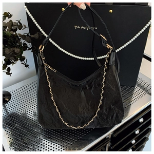 Gros plan sur le sac fourre-tout plissé noir avec chaîne dorée et bandoulière en cuir