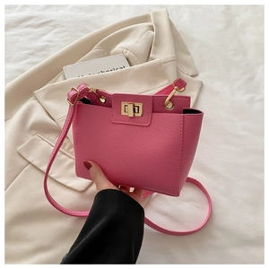 Gros plan d'un sac rose en cuir grainé avec fermoir rotatif doré et bandoulière réglable